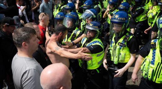 Anti-immigration protestors confronting a line of police officers in riot gear