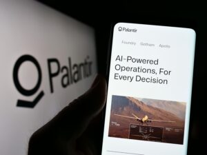 Person holding cellphone with website of US analytics company Palantir Technologies Inc. on screen with logo. Focus on center of phone display.
