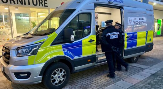 Essex police officers stand near a police van equipped with live facial recognition cameras in Harlow town centre